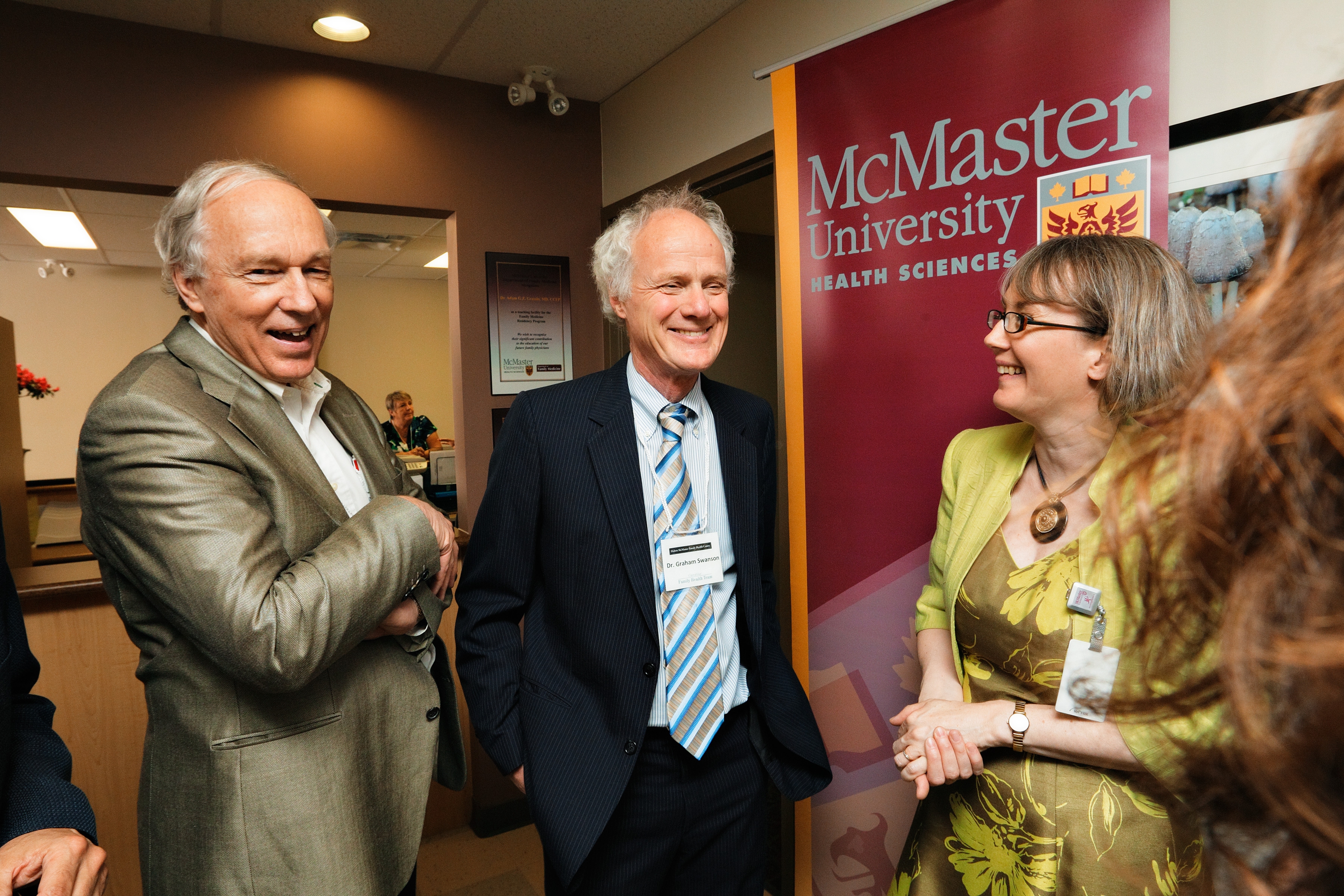 Three people stand in front of a maroon banner that says McMaster University Health Sciences on it