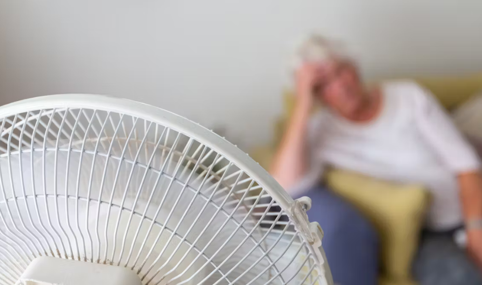 An older adult sitting in front of a fan